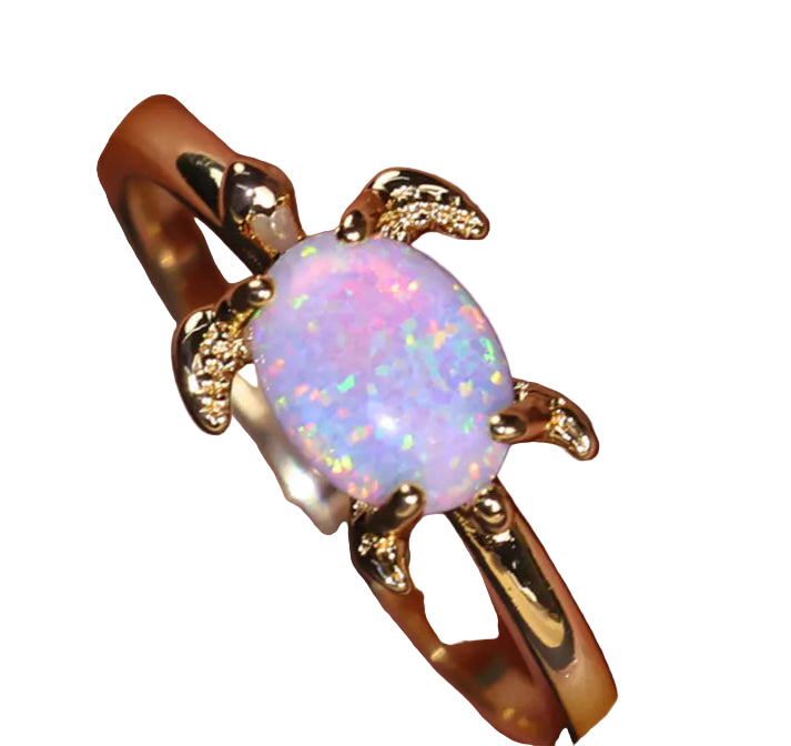 Gold ring with a pink opal stone on a hand against a dark background