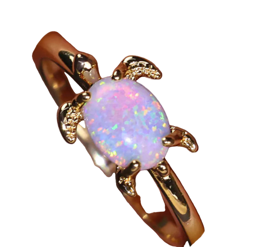 Gold ring with a pink opal stone on a hand against a dark background