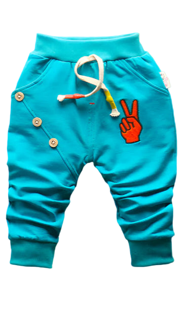 Turquoise children's pants with buttons and a peace sign on a woven mat