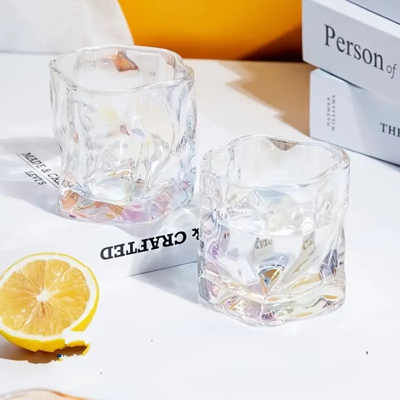 Two clear glass tumblers with a lemon wedge on a white surface.