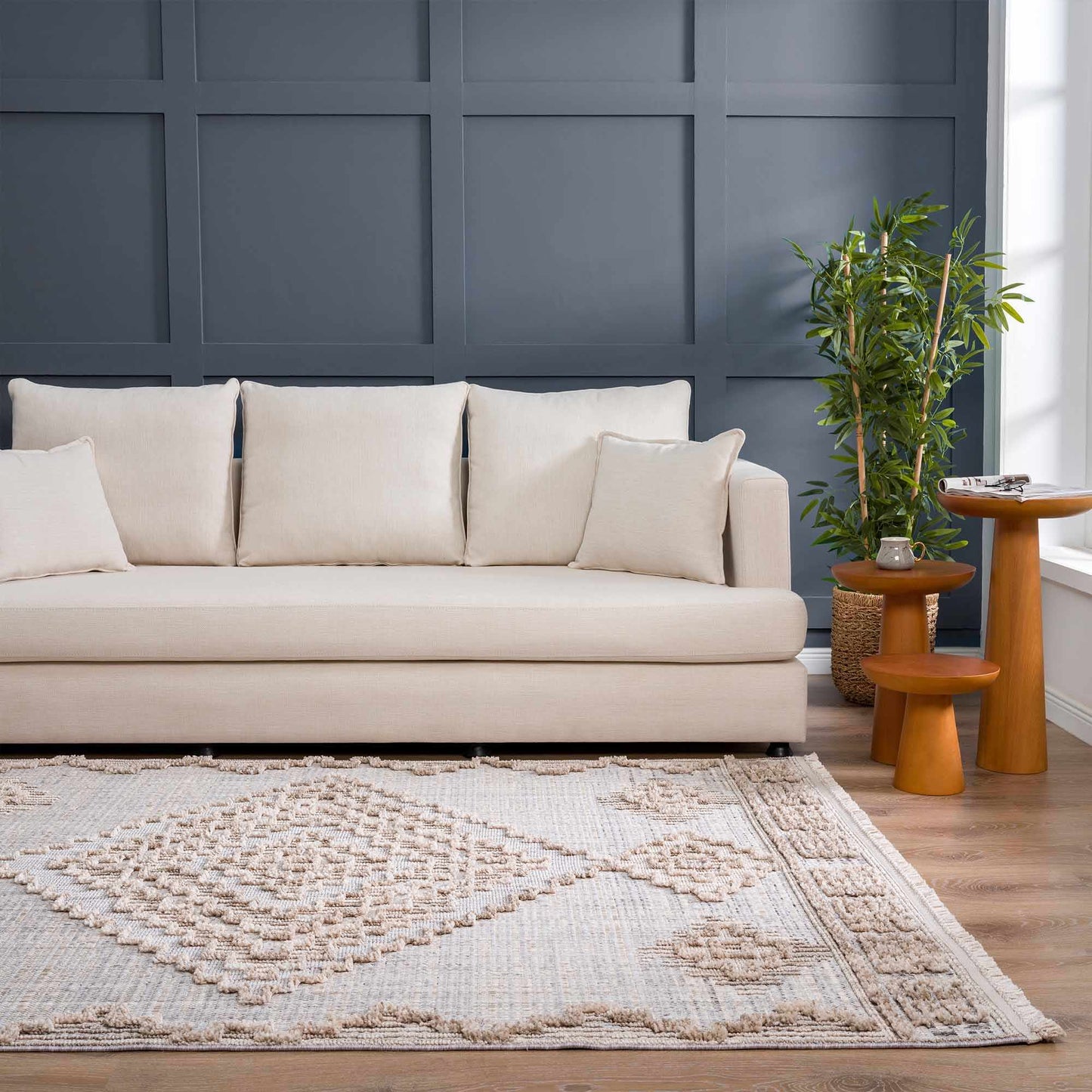 Beige sofa in a room with a dark blue paneled wall, a rug, and a small table with a plant.