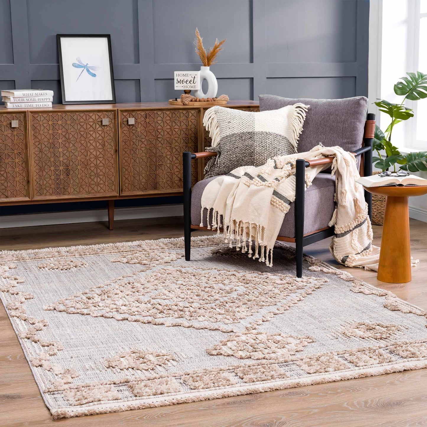 Living room with a gray armchair, patterned rug, and wooden sideboard.