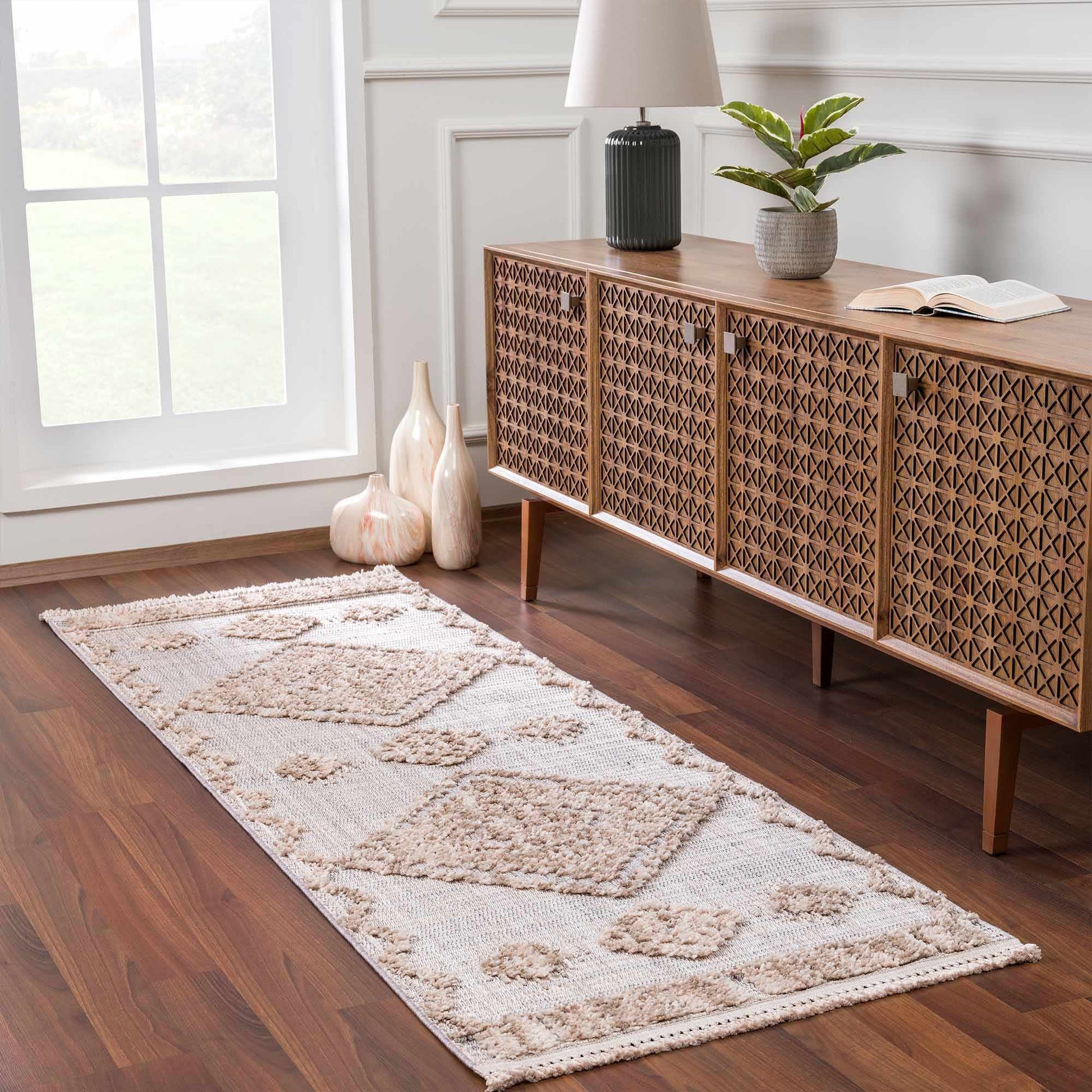 Beige patterned rug on a wooden floor with a wooden sideboard and decorative items.