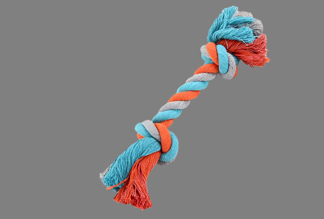 Colorful knotted rope toy on a white surface with a book in the background