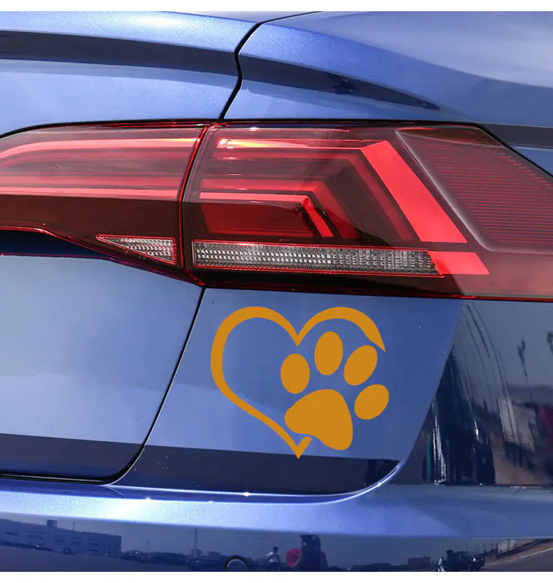 Yellow paw print inside a heart decal on a blue car's tail light.