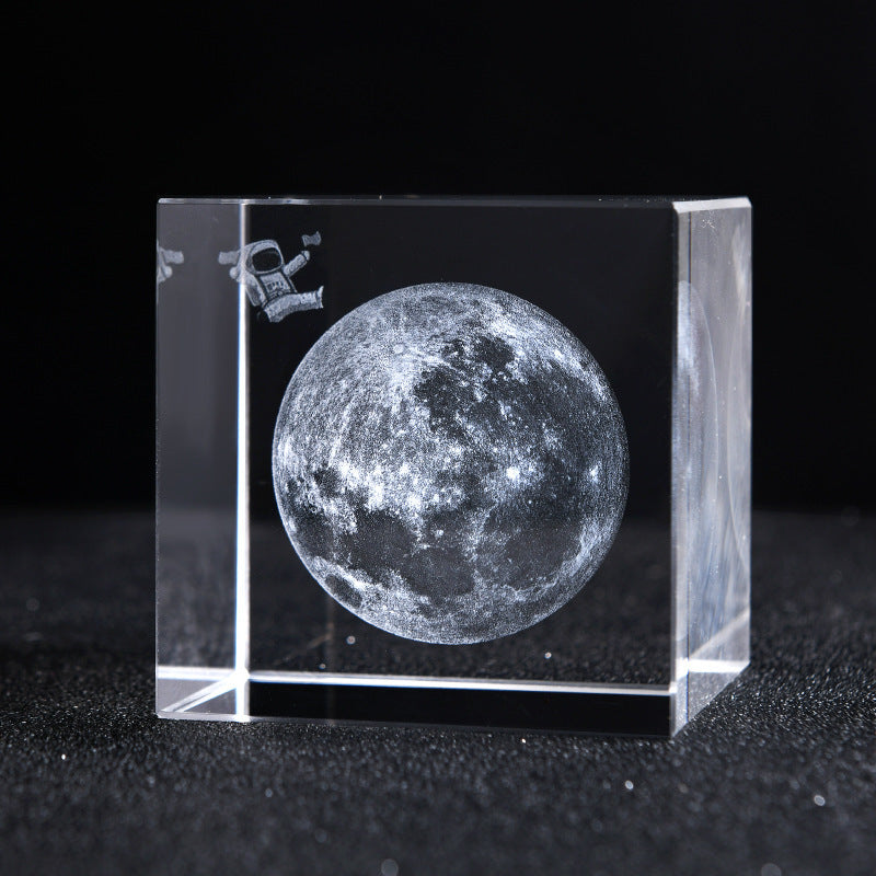 Crystal block with moon engraving and astronaut icon on a black background