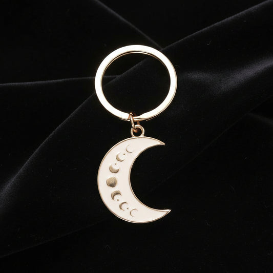 Gold keychain with a moon phase design on a white background