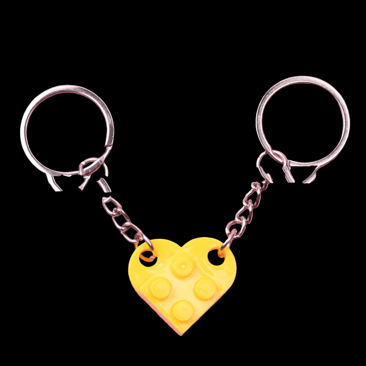 Yellow heart-shaped Lego piece keychain on a pink background