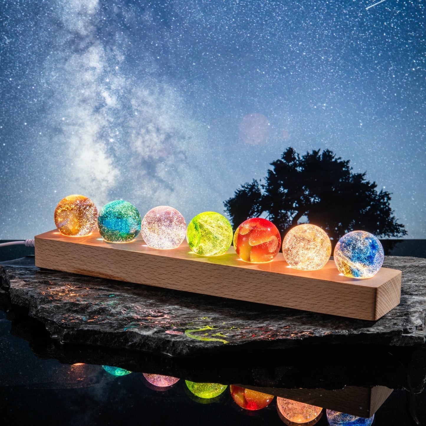 Colorful crystal balls on a wooden stand against a night sky with stars.