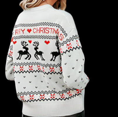 Woman wearing a festive sweater with reindeer and Christmas text, standing in front of a building entrance.