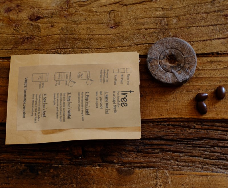 Brown paper bag with text on a wooden surface with coffee beans and a wooden grinder.