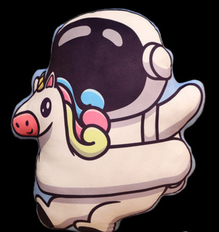 Unicorn astronaut plush toy on a couch with a plant and wooden shelf in the background