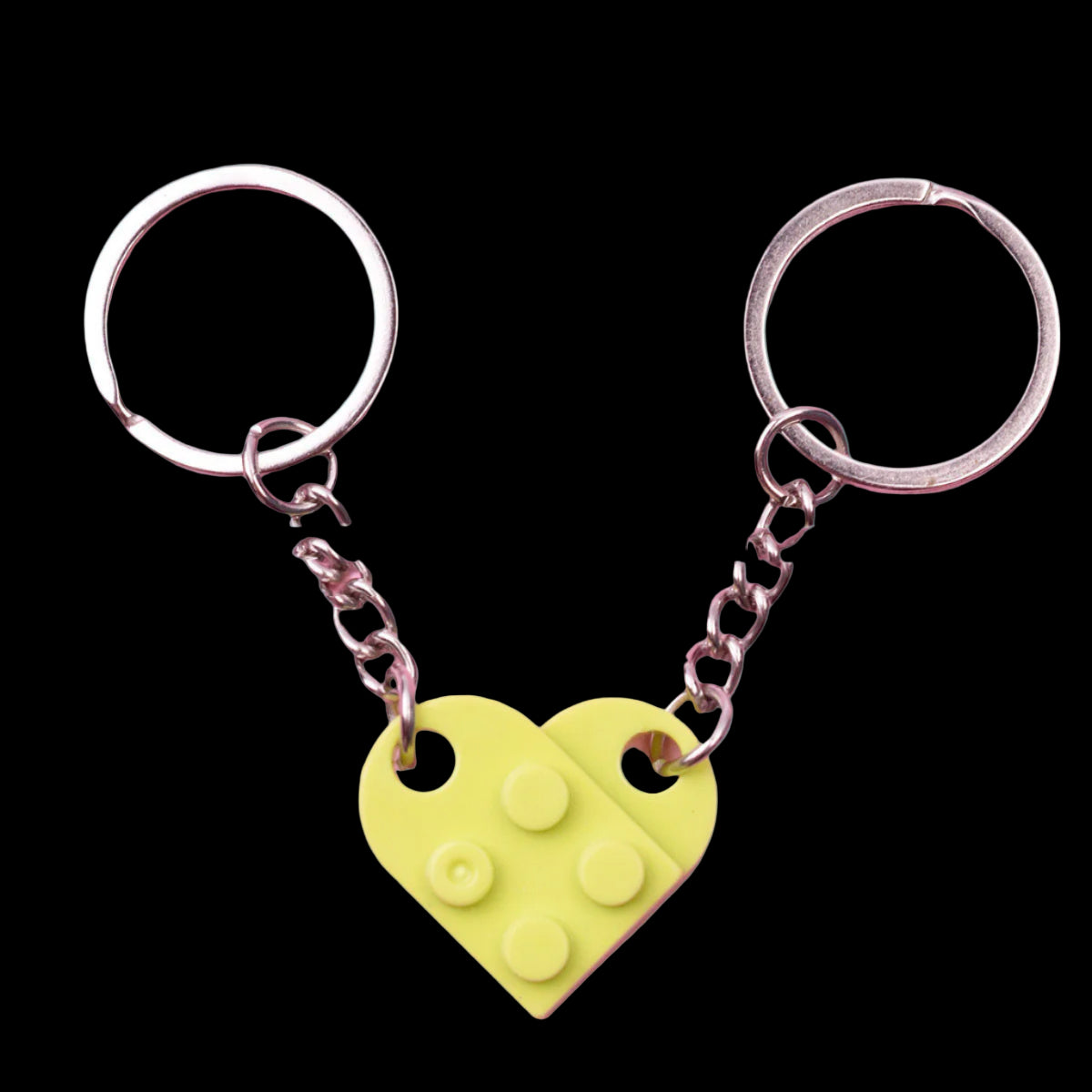 Two keychains with heart-shaped LEGO piece pendants on a pink background
