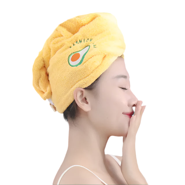 Person wearing a yellow hair towel with an avocado design, touching their face.