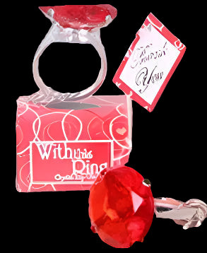 Red gemstone ring in a clear box with a tag on a decorative plate.