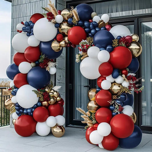Balloon arch with red, white, and blue balloons and floral decorations in front of a building.