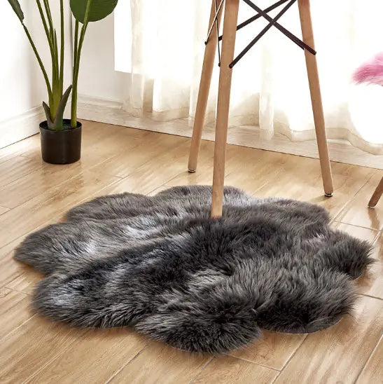 Gray faux fur rug on a wooden floor with a plant and chair in the background