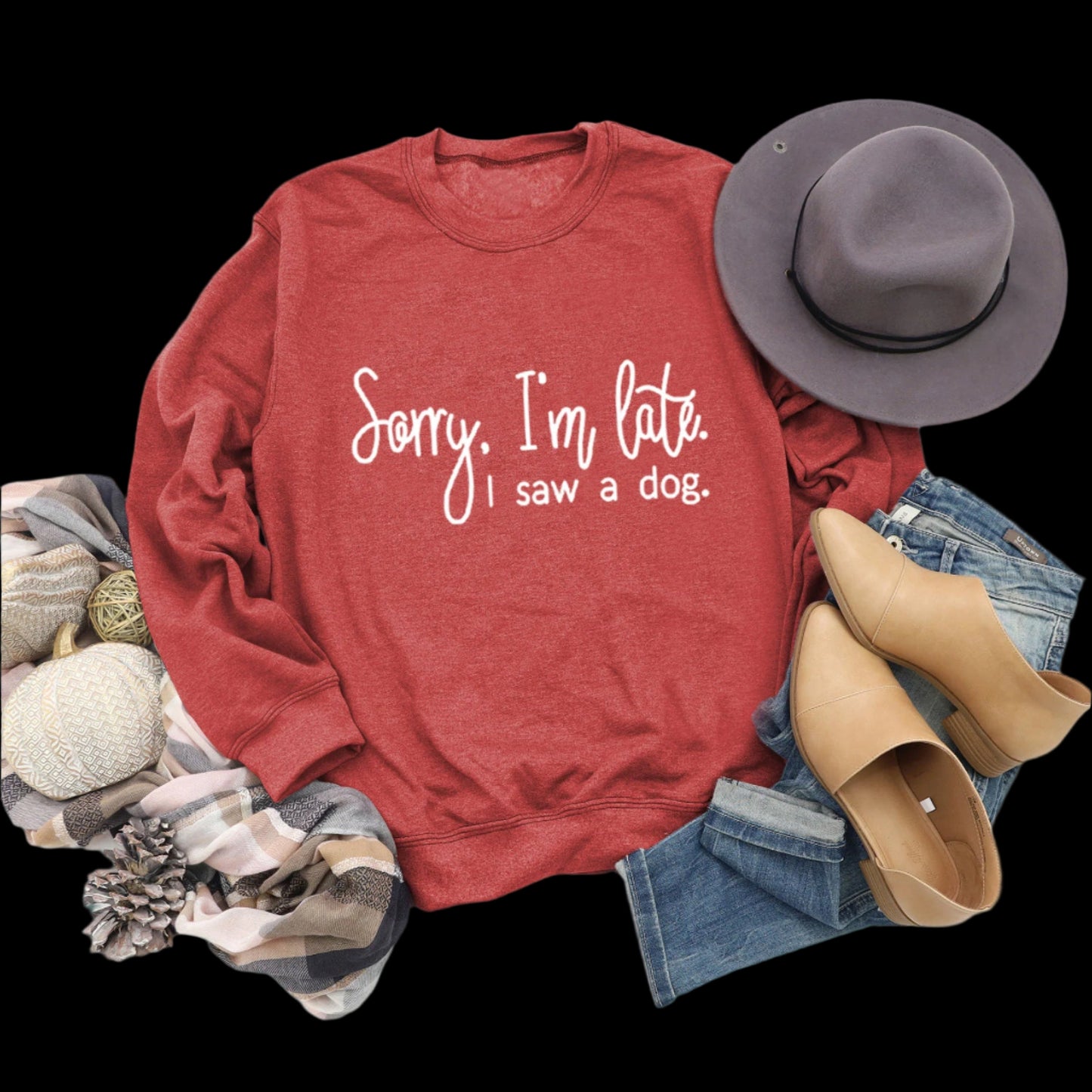 Red sweatshirt with text, hat, boots, and jeans on a wooden surface