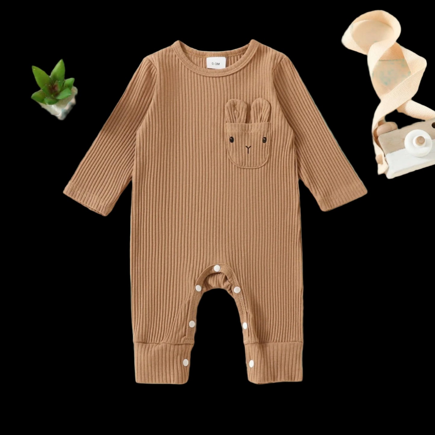 Brown ribbed baby onesie with bunny ears and nose on a beige background