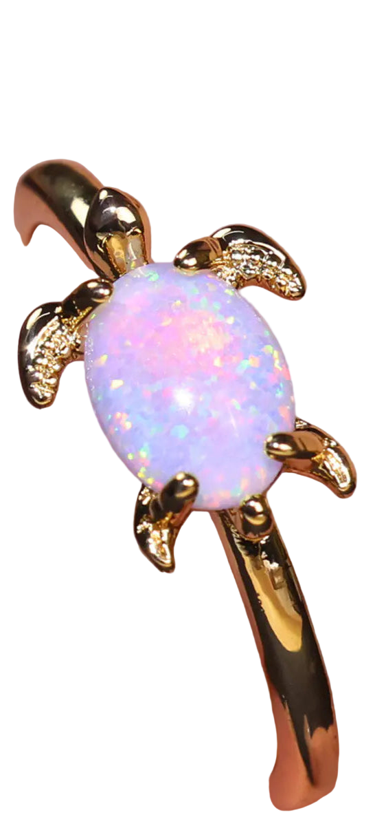 Gold turtle-shaped earring with a pink opal stone on a blurred background