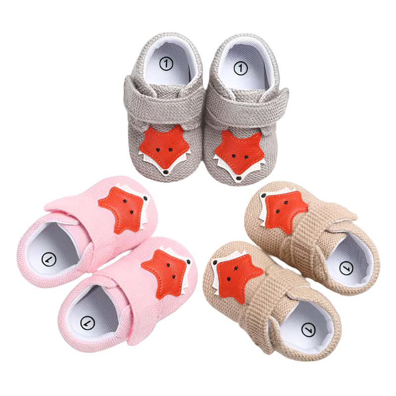 Set of baby shoes with fox face design in gray, pink, and beige on a white background