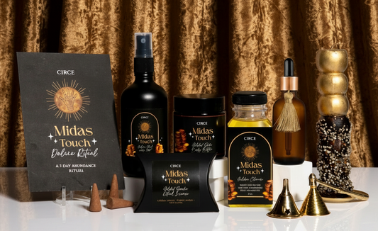 Collection of Midas Touch products including bottles, candles, and a book on a white background