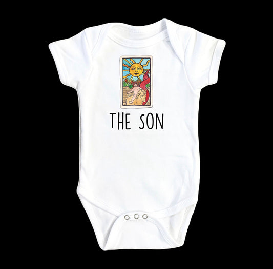 White baby onesie with 'The Son' text and Tarot card design on a white background