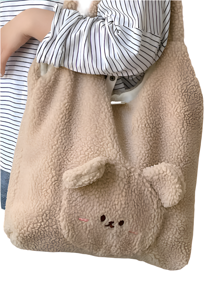Person holding a fluffy beige bag with bear ears and a face, standing in a room.