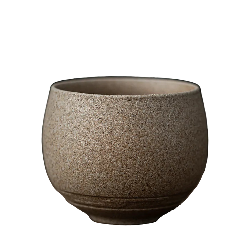 Textured ceramic cup on a wooden surface with a dark background