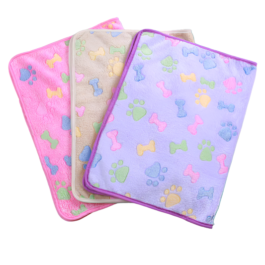 Three pet towels with colorful paw and bone patterns on a beige carpet.