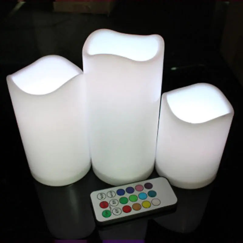 Set of three LED candle lights with a remote control on a dark surface
