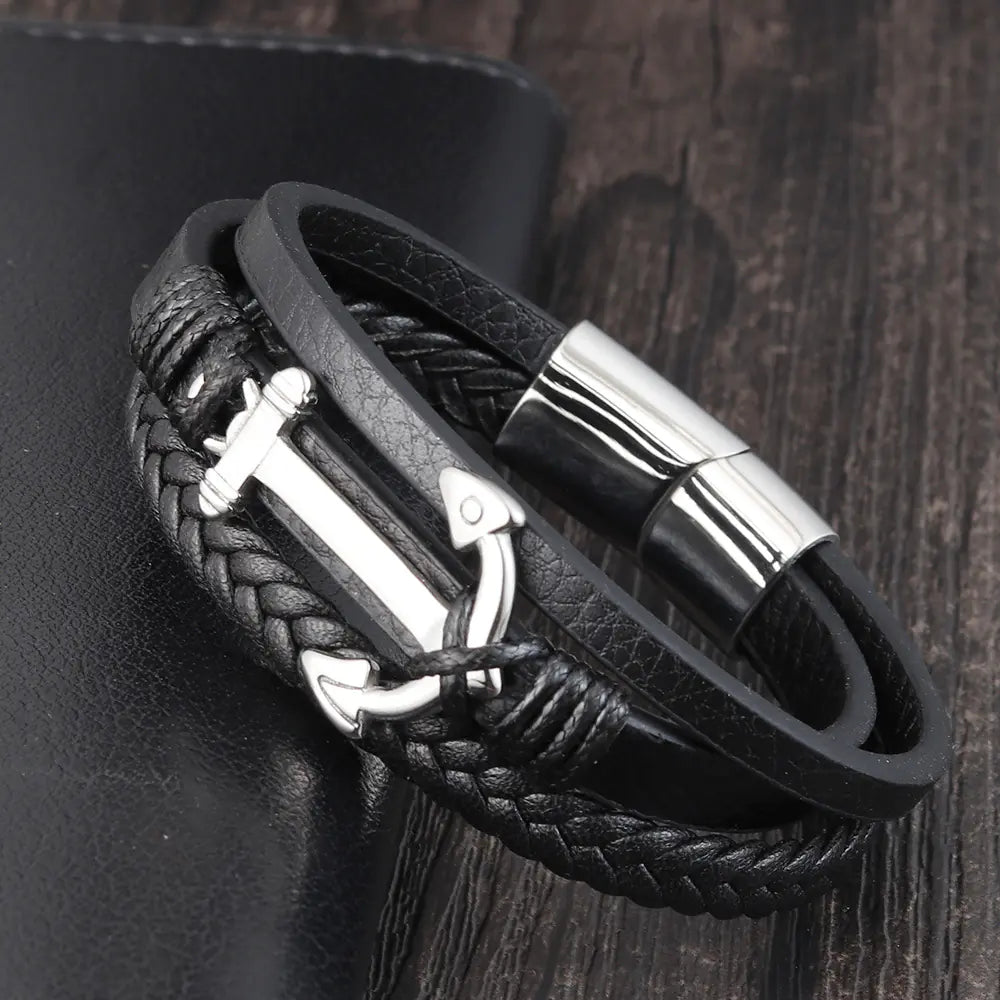 Black braided leather bracelet with silver clasp on a dark wooden surface
