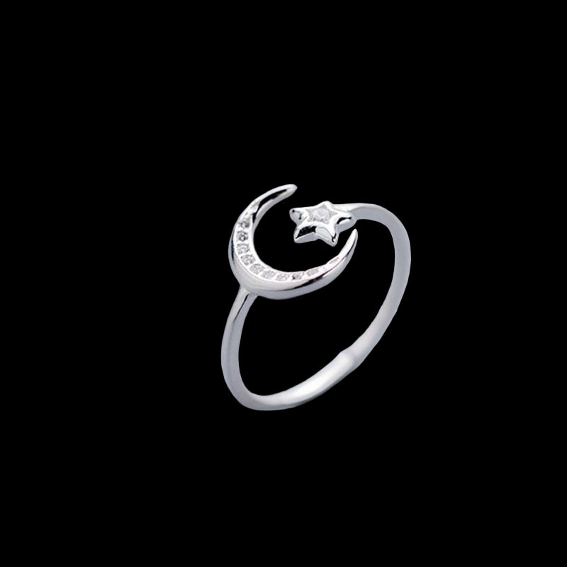 Silver ring with moon and star design on a light gray background