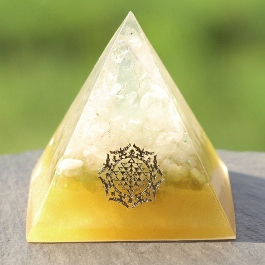 Pyramid-shaped crystal with a symbol on a stone surface and blurred green background