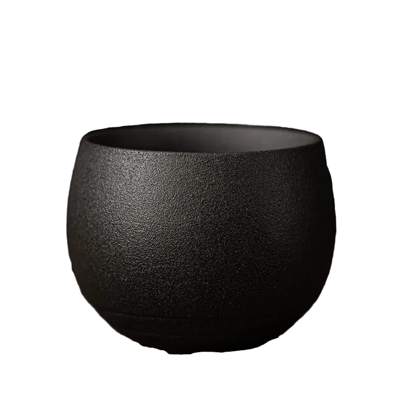 Black ceramic cup on a wooden surface with a dark background
