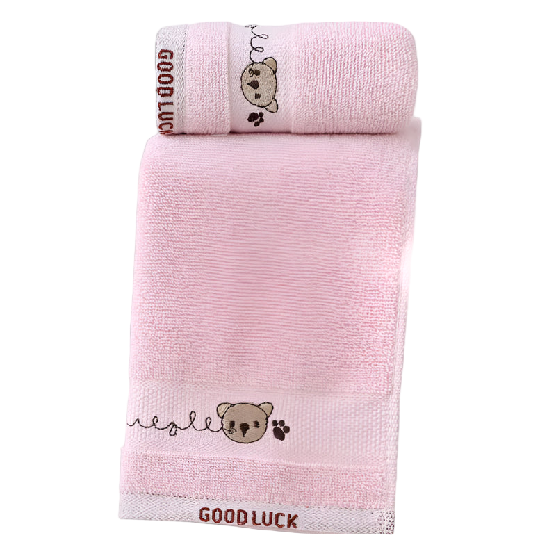 Two pink towels with embroidered teddy bear designs and 'GOOD LUCK' text on a white background.