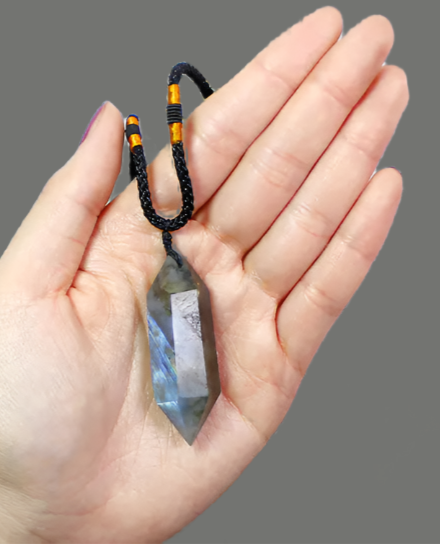 Hand holding a black beaded necklace with a magazine in the background