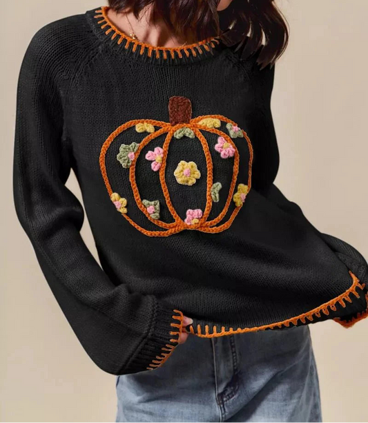 Black sweater with a pumpkin design on a beige background