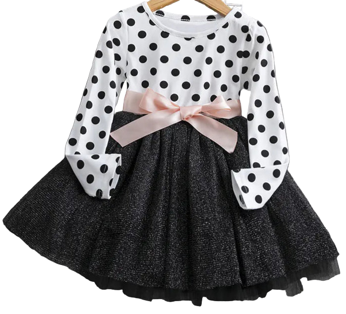 Polka dot blouse with a pink bow and black pleated skirt on a wooden surface.