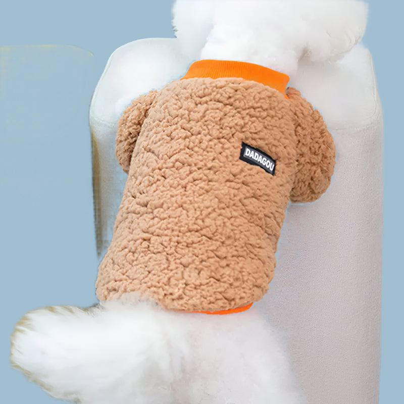 Dog wearing a fluffy brown sweater with an orange trim, sitting on a yellow chair.