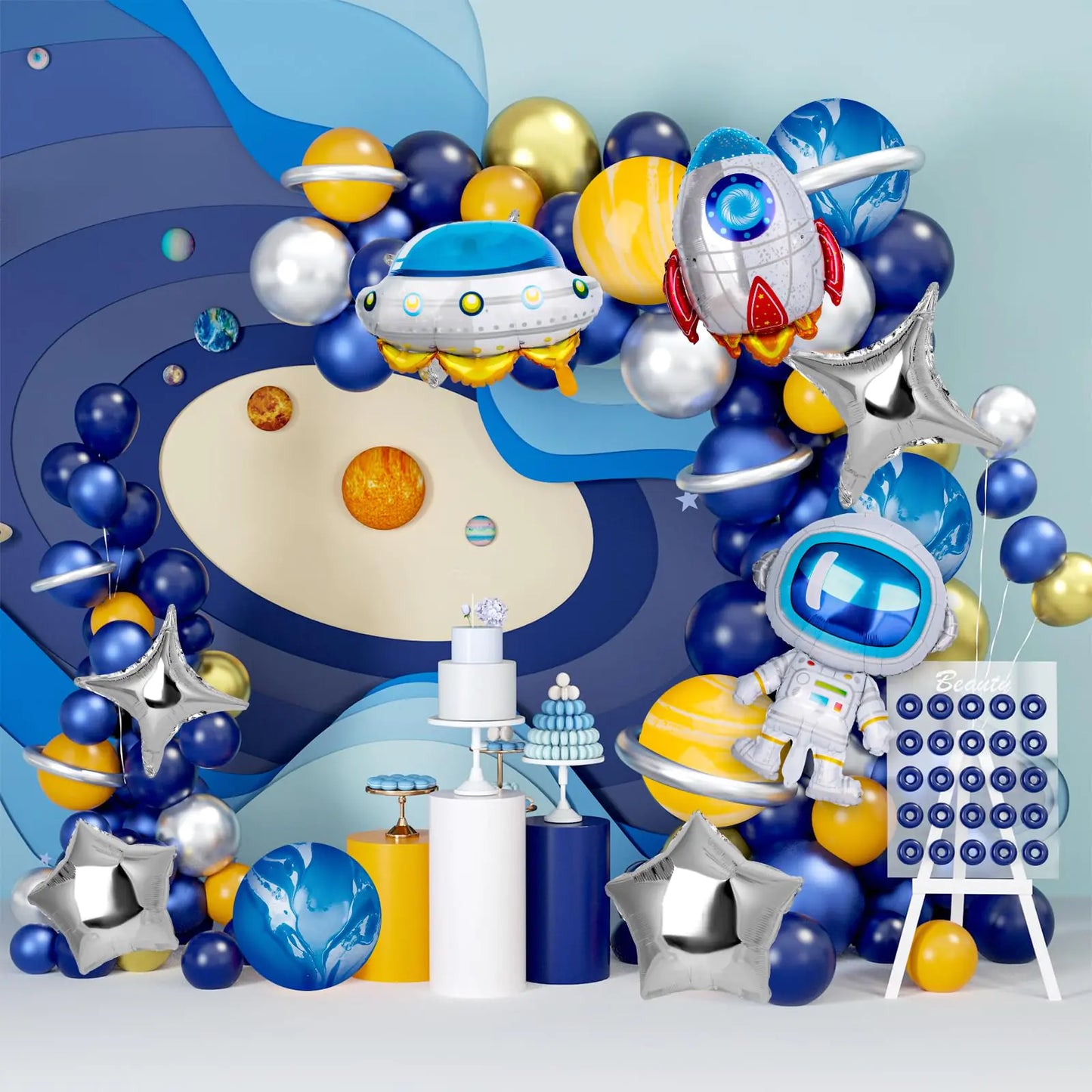 Space-themed balloon arch with planets, stars, and astronaut decorations against a blue background.