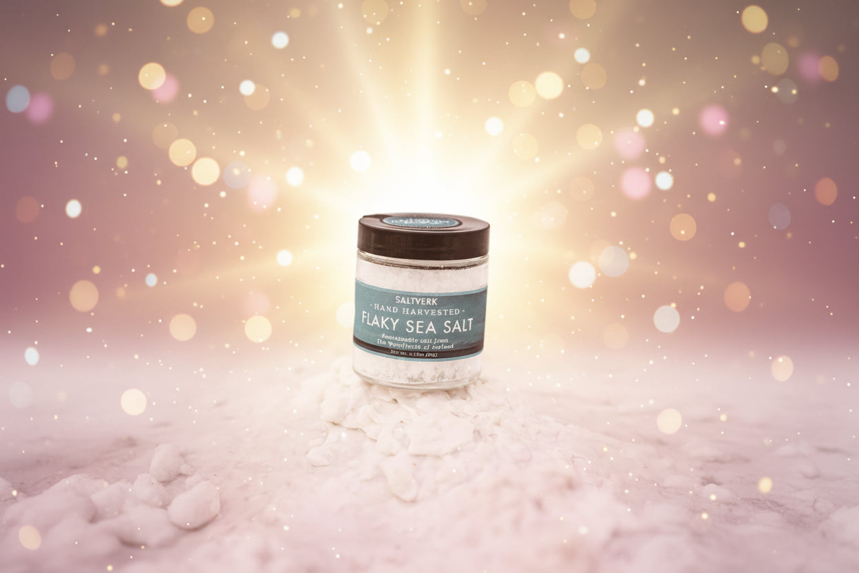 Jar of flaky sea salt with a blue label on a white background