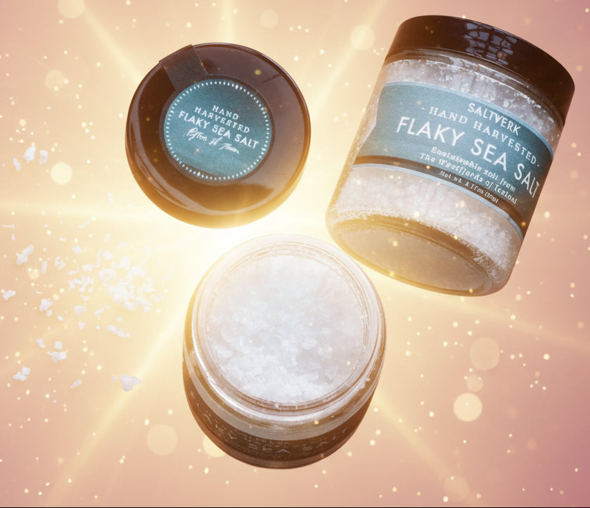Three jars of flaky sea salt on a textured surface