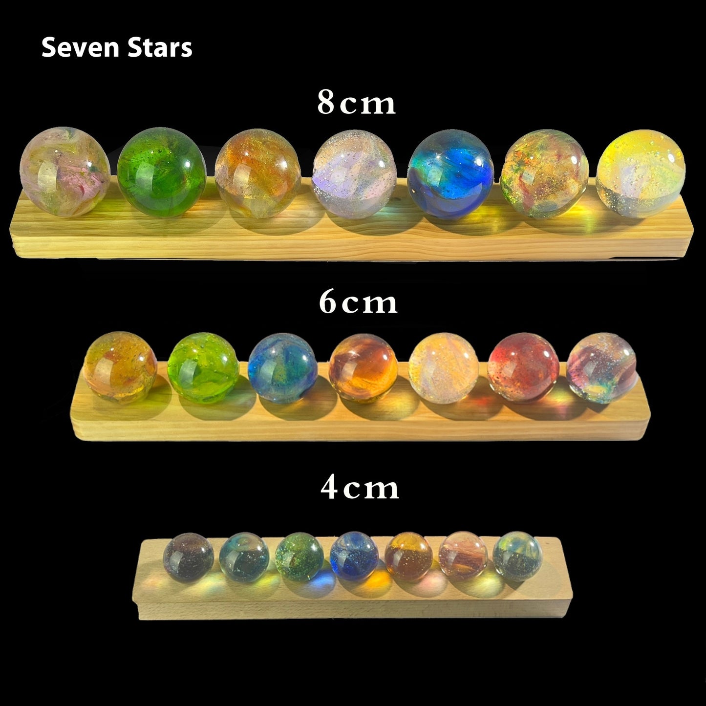Colorful marbles on wooden stands with size measurements.