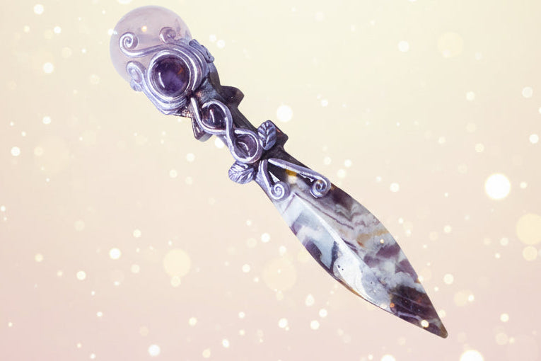 Decorative dagger with purple gemstone on a white surface