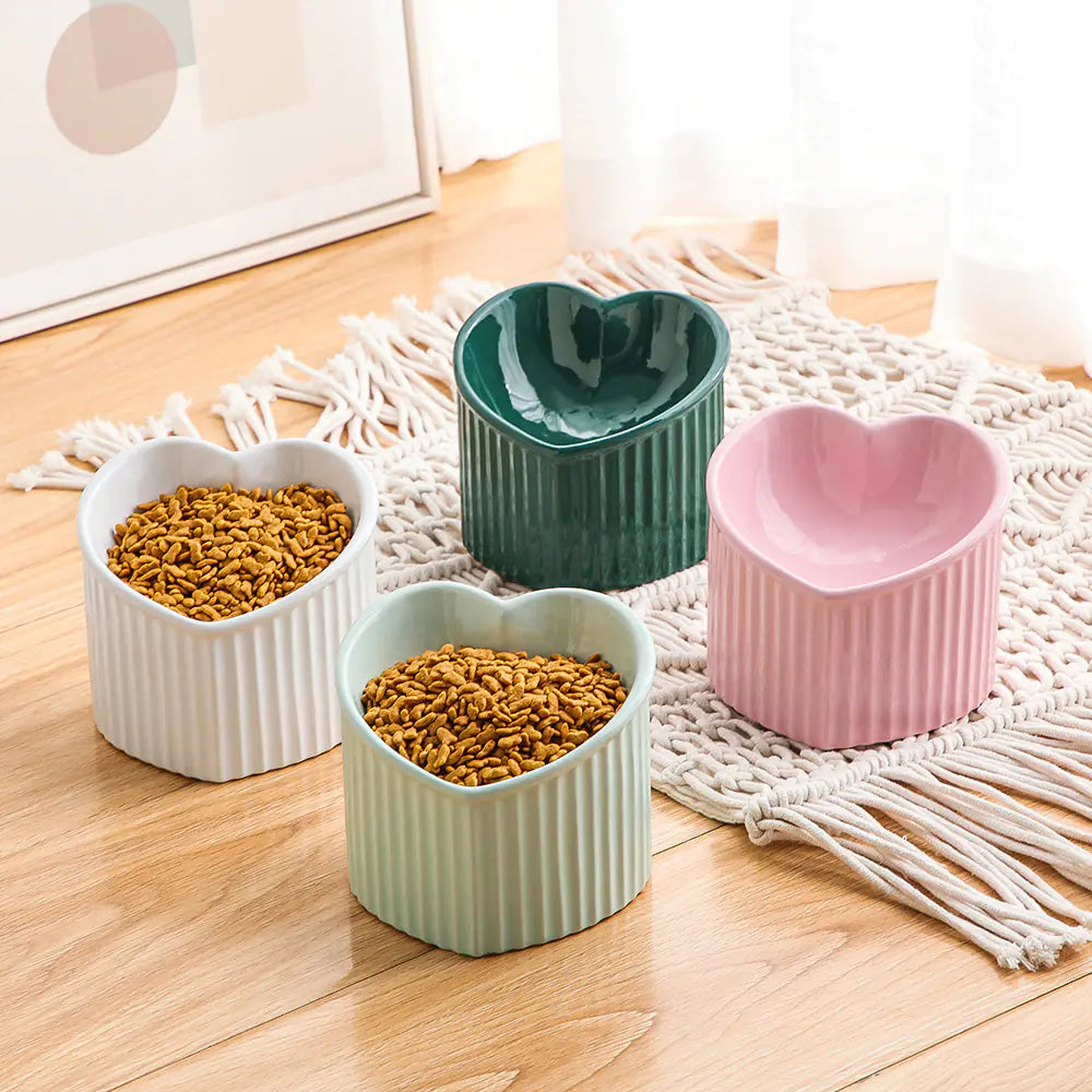 Set of four heart-shaped ceramic bowls on a wooden floor with macrame rug.