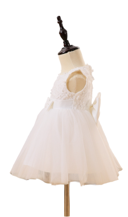 White lace dress on a mannequin in a room with a bookshelf and curtains.