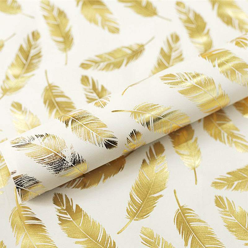 Roll of gold feather patterned paper on a white background