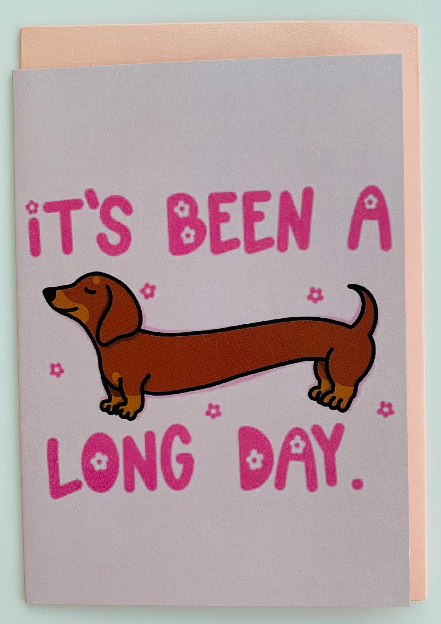 Card with a dachshund illustration and text 'It's been a long day' on a light blue background