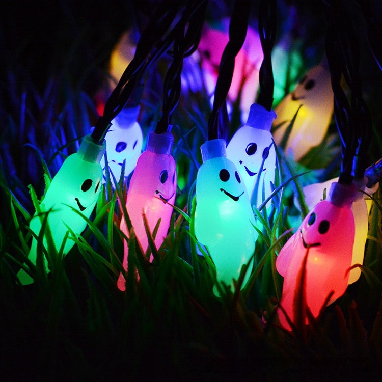 String lights shaped like ghosts in green, pink, and red on grass
